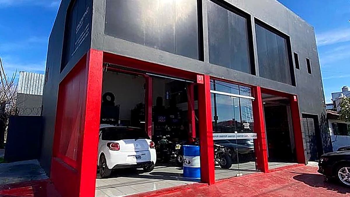 Frente del taller D'Agostino Motorsport en Tolosa: fachada gris y roja con los dos boxes abiertos y vehículos adentro.